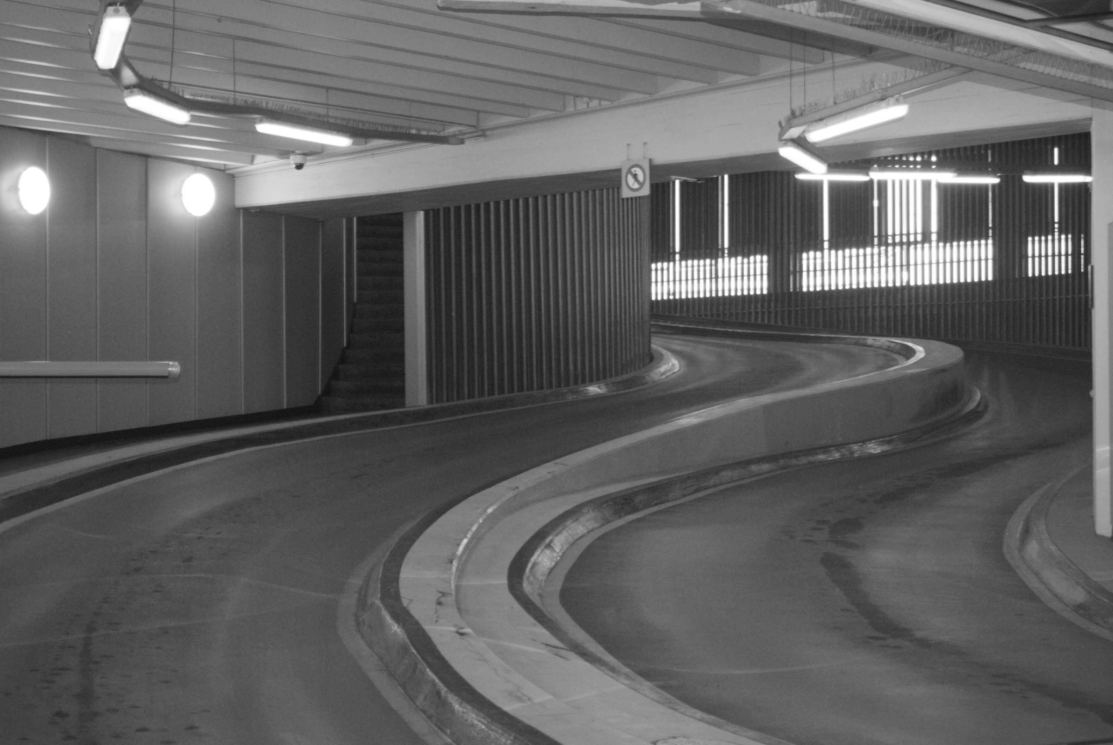 A spiralling parking ramp lit by fluorescent tubes