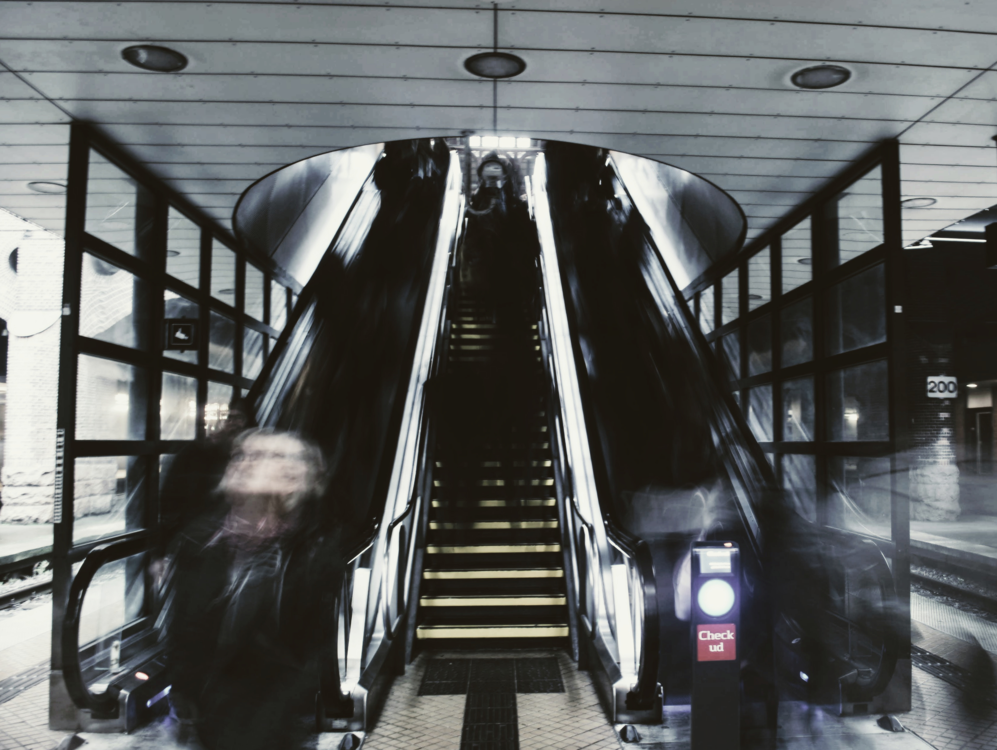 An escalator descending into a station, a figure blurred in motion