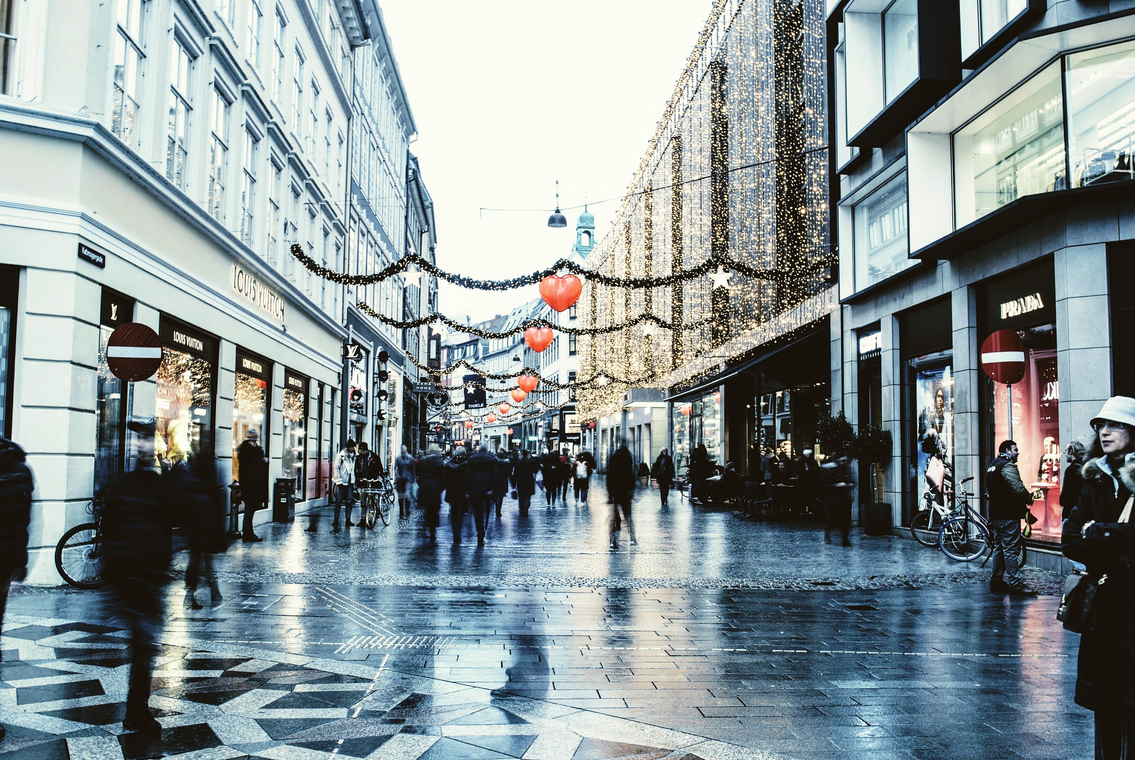 A pedestrian shopping street strung with Christmas lights, blurred figures