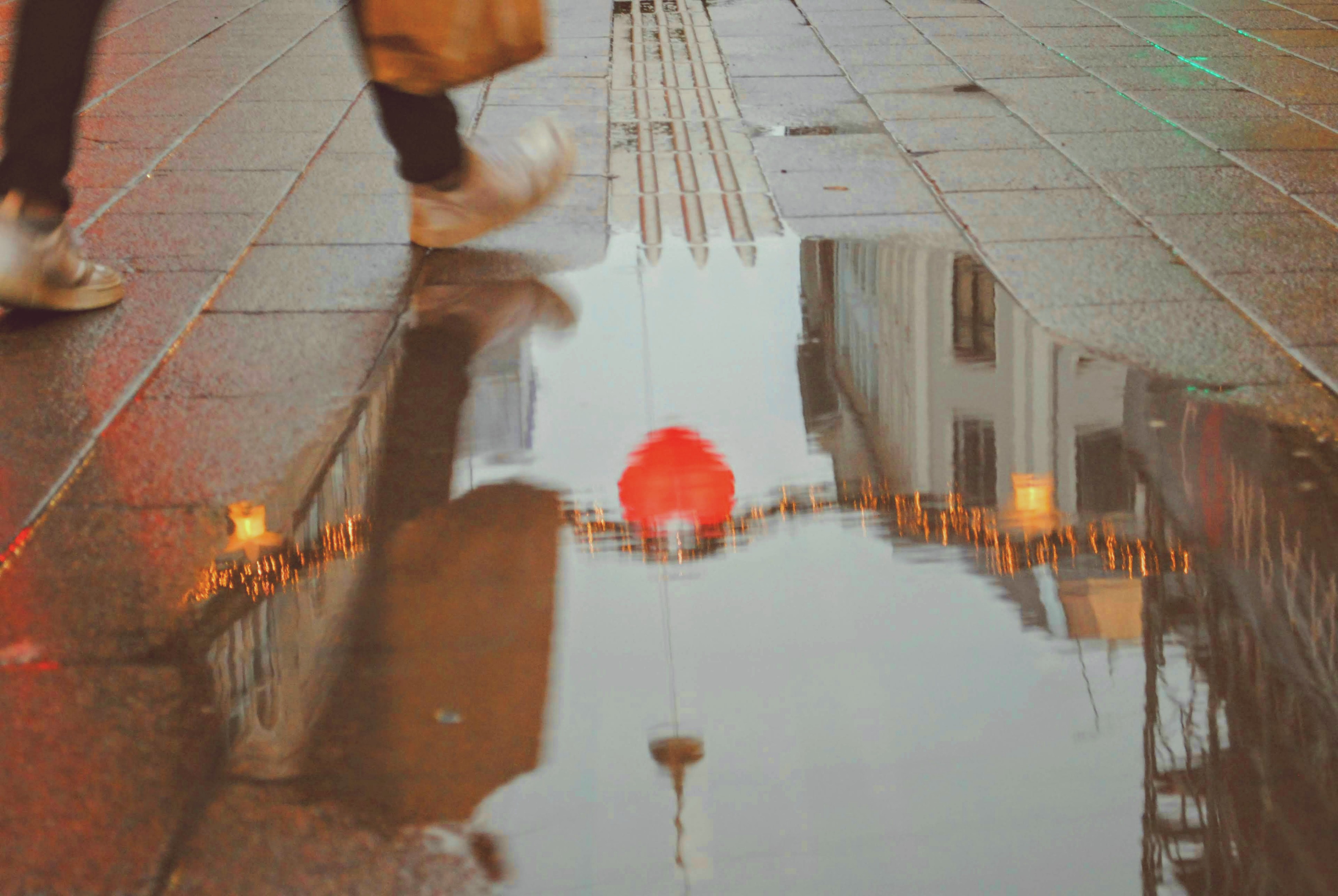 A red umbrella reflected upside-down in a puddle